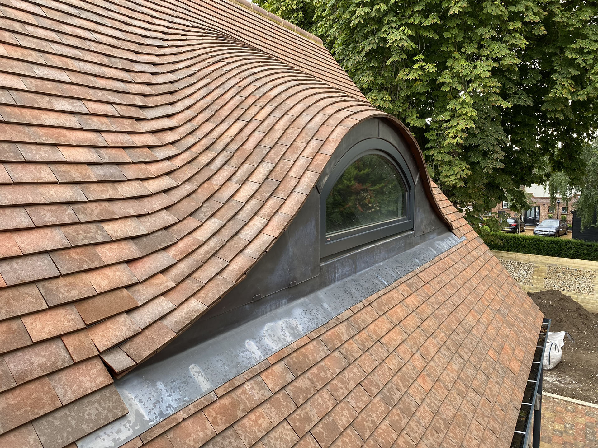 an eyebrow roof detail on a small residential development by NP Architects with Dreadnought Country Brown sanded tiles